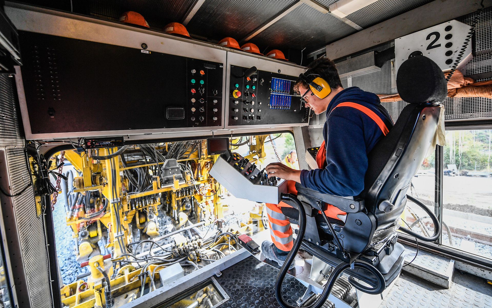 Innenaufnahme einer Gleisbaumaschine mit Triebfahrzeugführer auf dem Triebfahrzeugführersitz