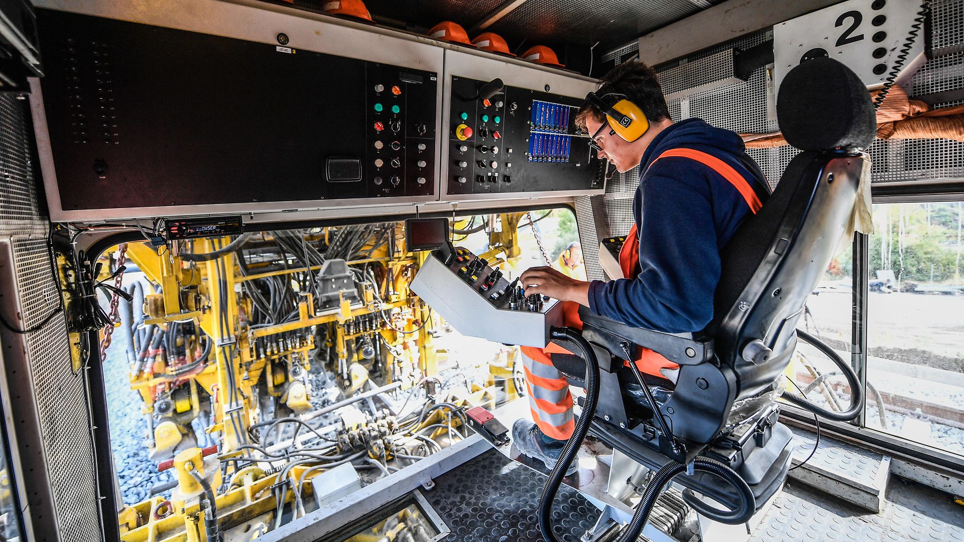 Innenaufnahme einer Gleisbaumaschine mit Triebfahrzeugführer auf dem Triebfahrzeugführersitz