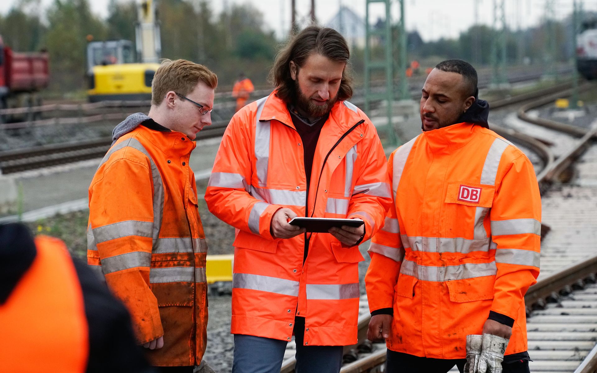 Mitarbeiter zeigt zwei anderen etwas auf dem Tablet