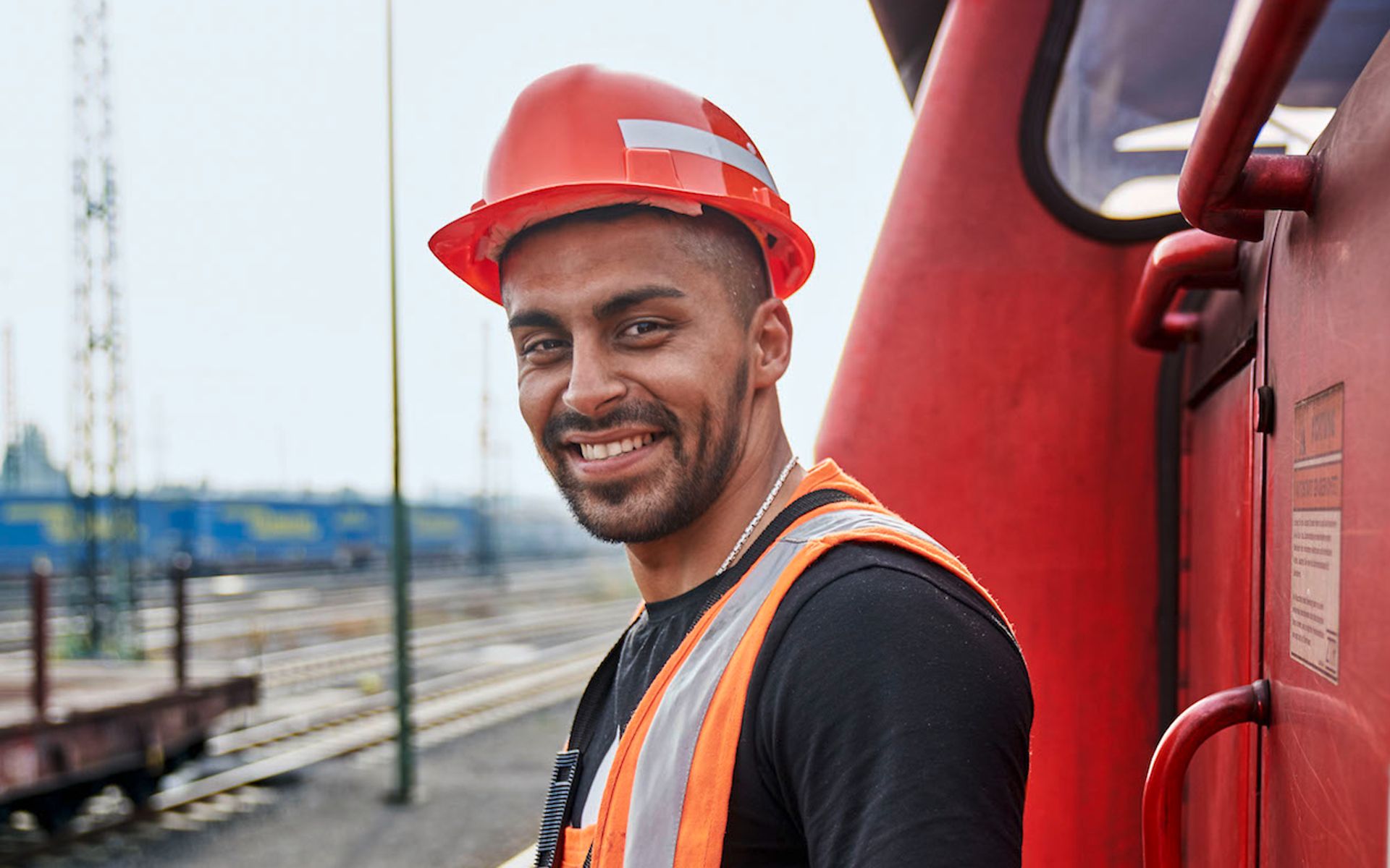 Mitarbeiter steht lächelnd neben einem roten Zug