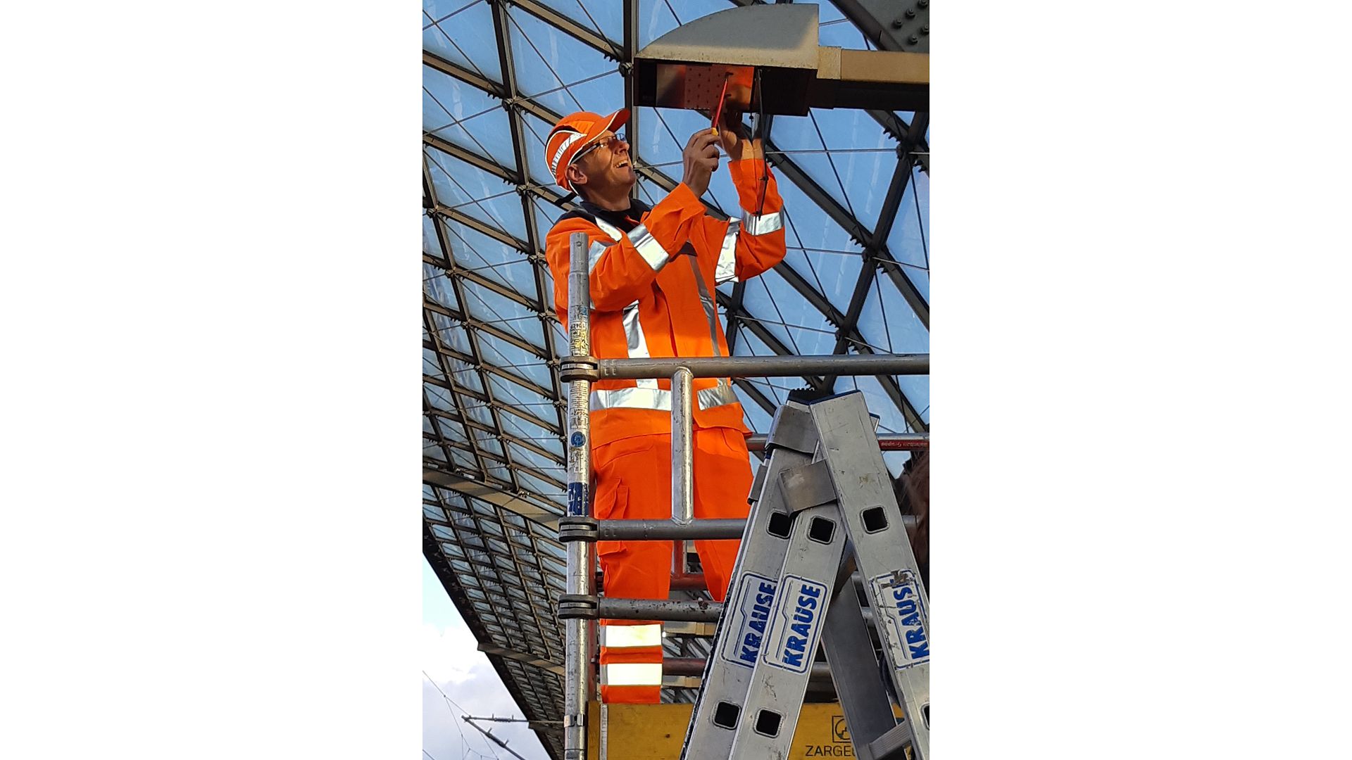 Mitarbeiter baut LED-Leuchtmittel in eine Lampe am Bahnhof ein