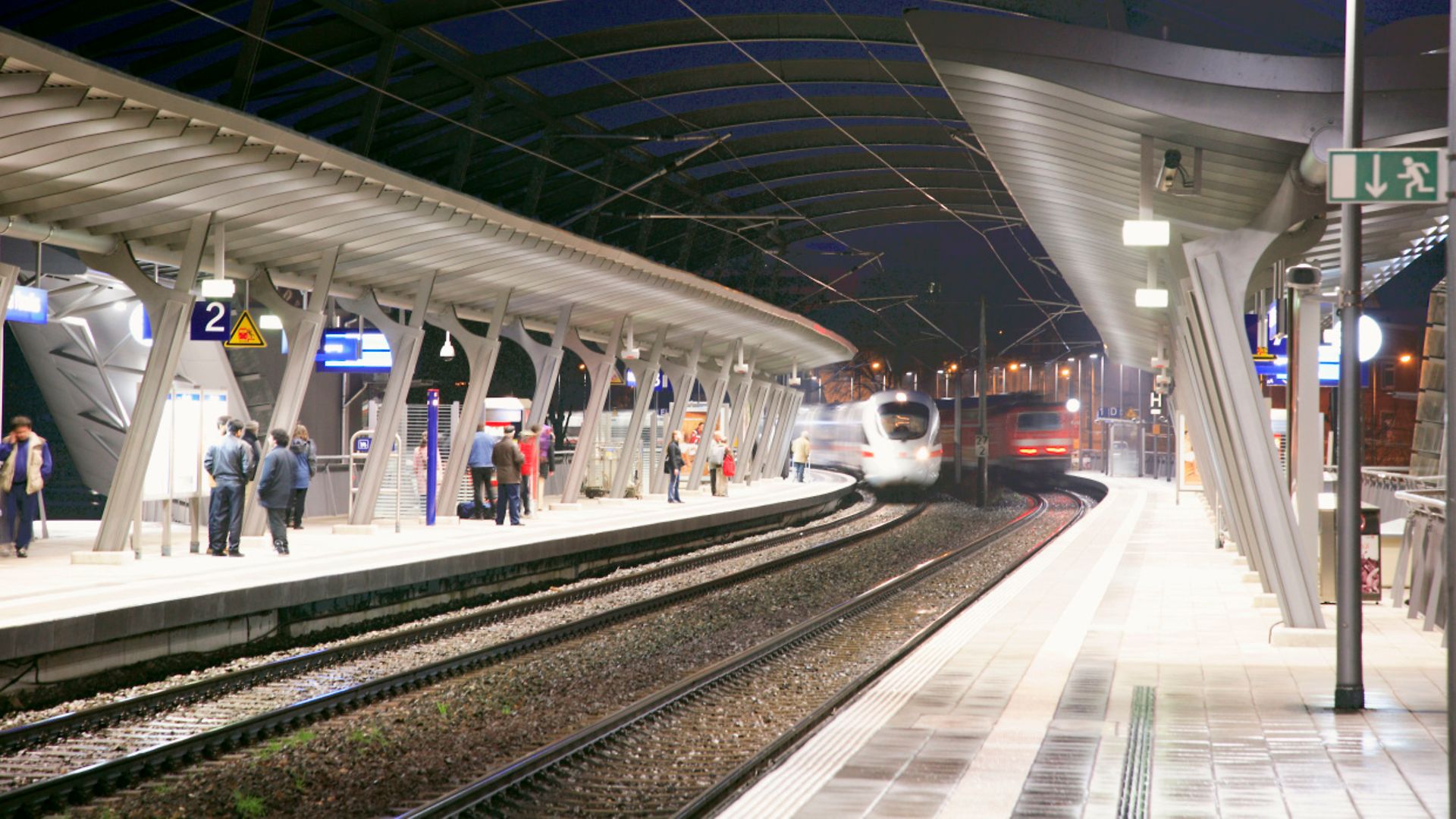 moderner Bahnsteig mit einfahrenden ICE bei Nacht