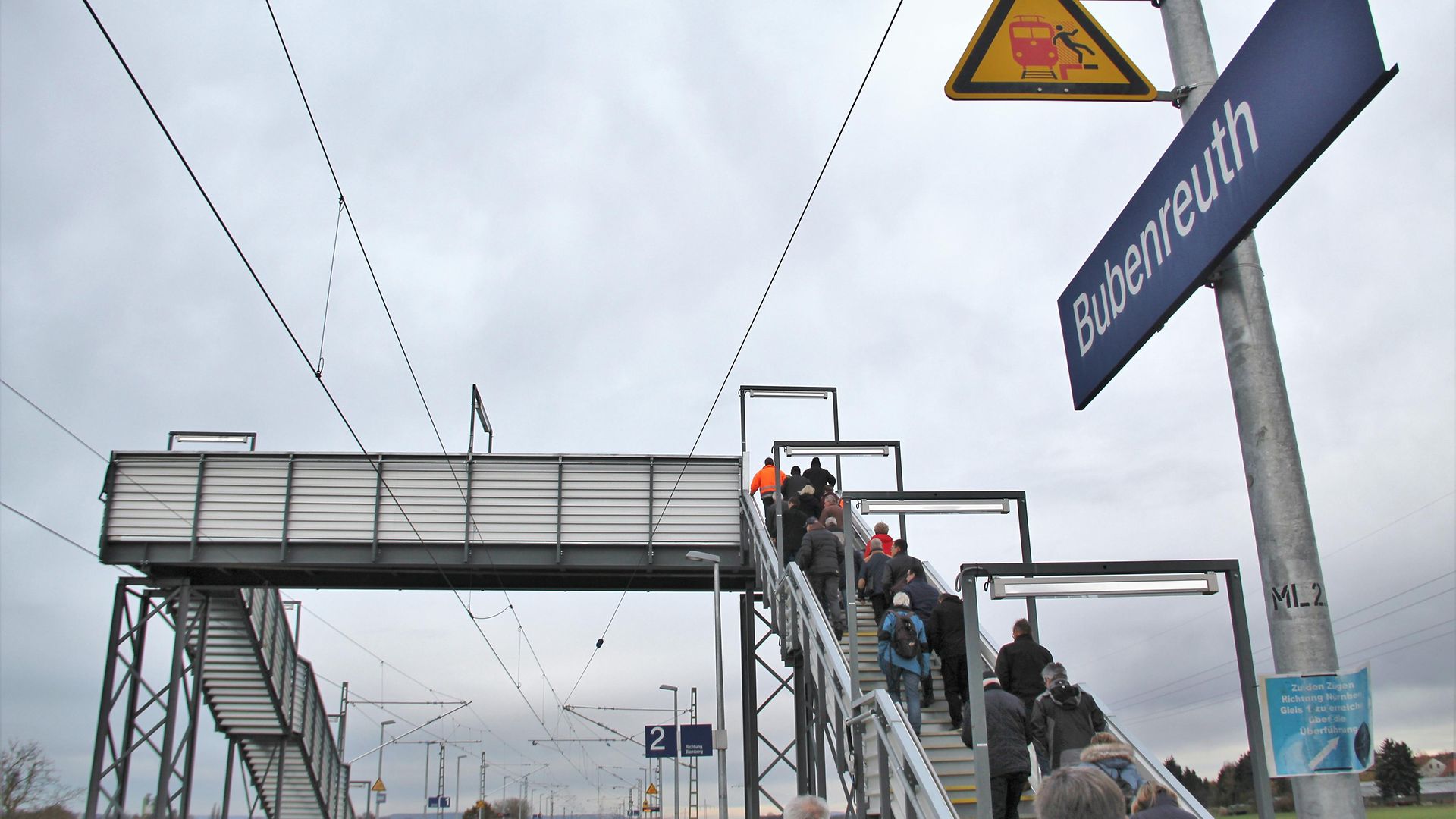Fahrgäste laufen die Treppe einer Fußgängerbehelfsbrücke hoch