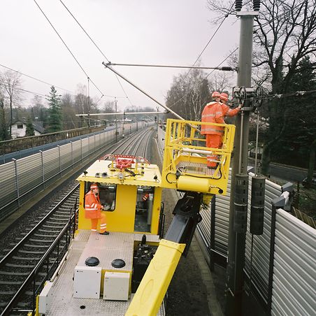 gelbe Maschine mit Kran zur Arbeit an Oberleitungen
