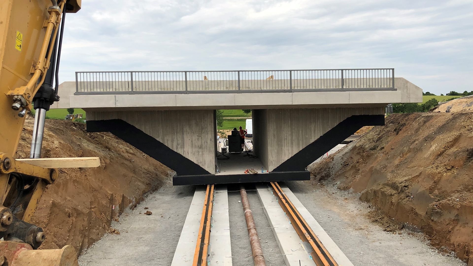 Einschub einer Eisenbahnüberführung auf Schienen mit gelben Kran
