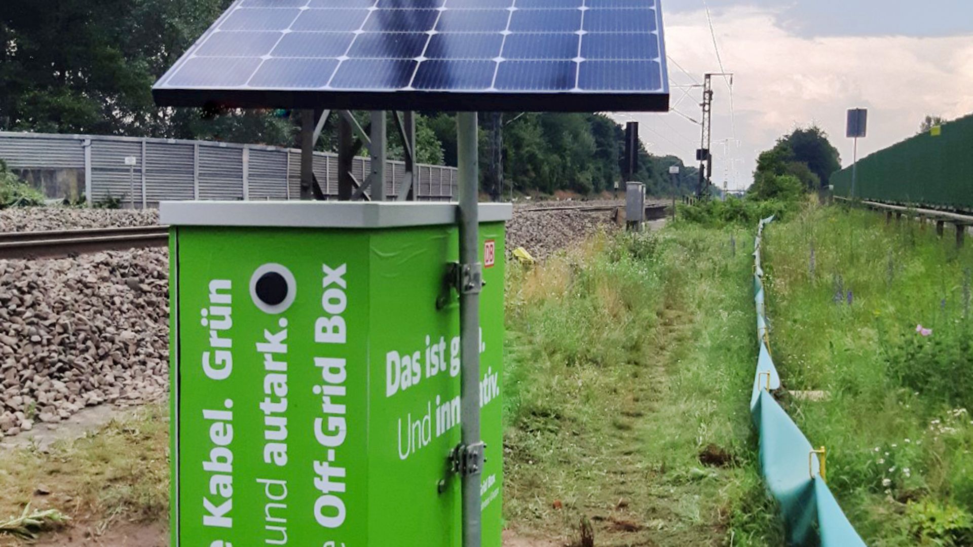 grüne Box mit Photovoltaikanlage als Energieversorgung an Strecke.