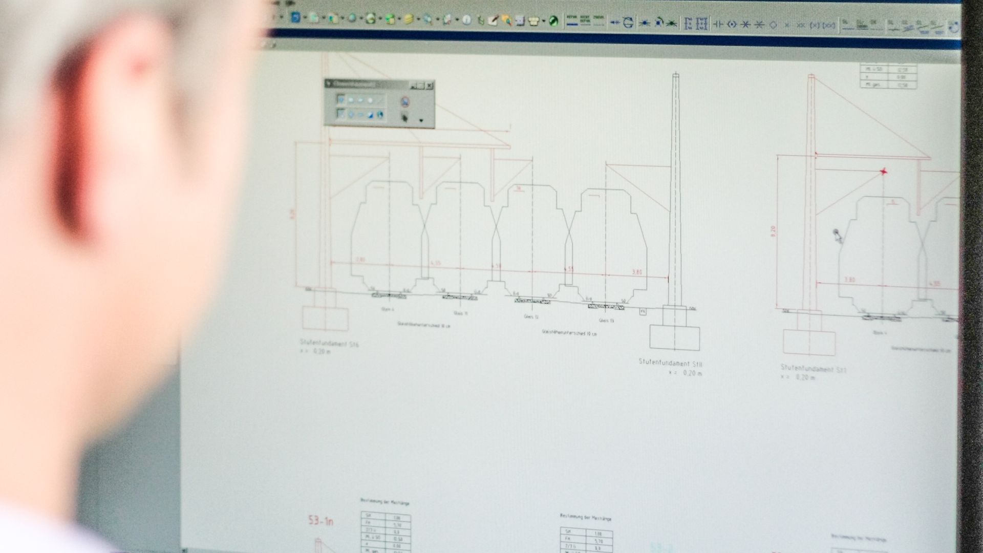 Blick über die Schulter eines Mitarbeiters auf seinem Monitor mit Blick auf die Planung von Gleisen und Stufenfundamenten.