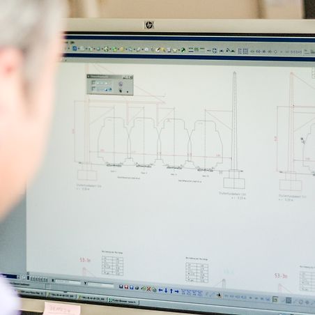 Blick über die Schulter eines Mitarbeiters auf seinem Monitor mit Bauplan.