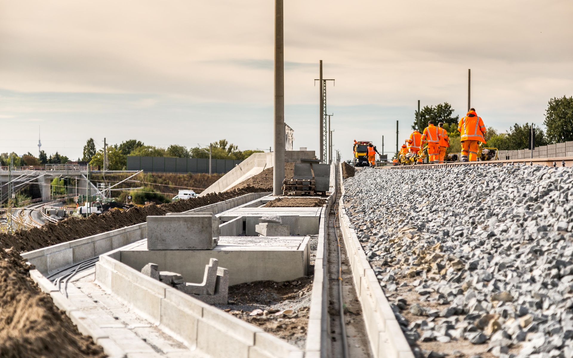 Kabelkanäle neben Zugstrecke. Mitarbeiter arbeiten am Gleis