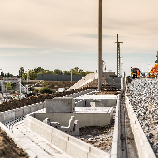 Kabelkanäle neben Zugstrecke. Mitarbeiter arbeiten am Gleis