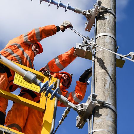 Mitarbeiter arbeiten an Oberleitungsmasten