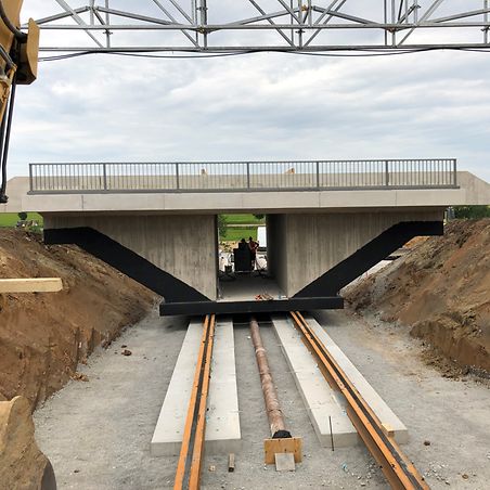 Einschub einer Eisenbahnüberführung auf Schienen mit gelben Kran