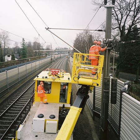 gelbe Maschine mit Kran zur Arbeit an Oberleitungen