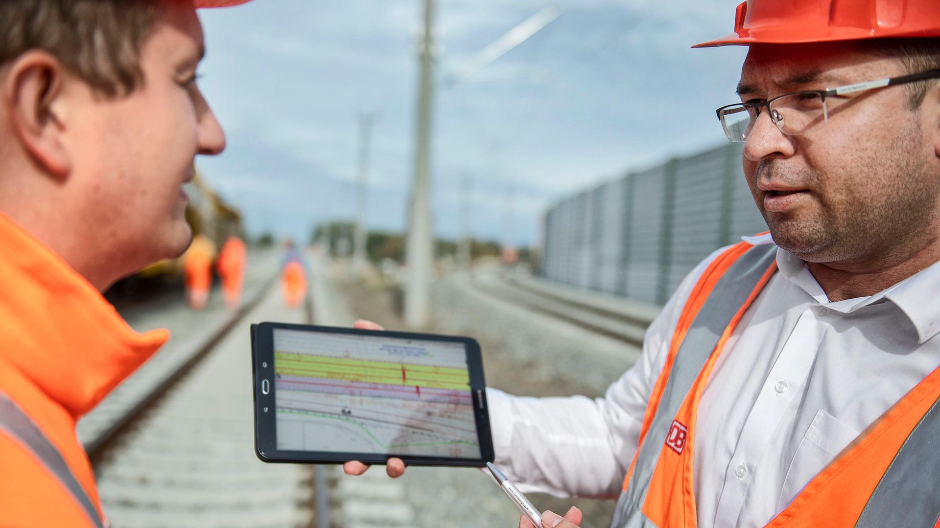 zwei Mitarbeiter mit Tablet in der Hand planen weitere Schritte der Gleisarbeiten