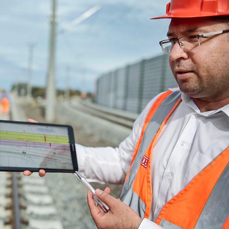 zwei Mitarbeiter mit Tablet in der Hand planen weitere Schritte der Gleisarbeiten