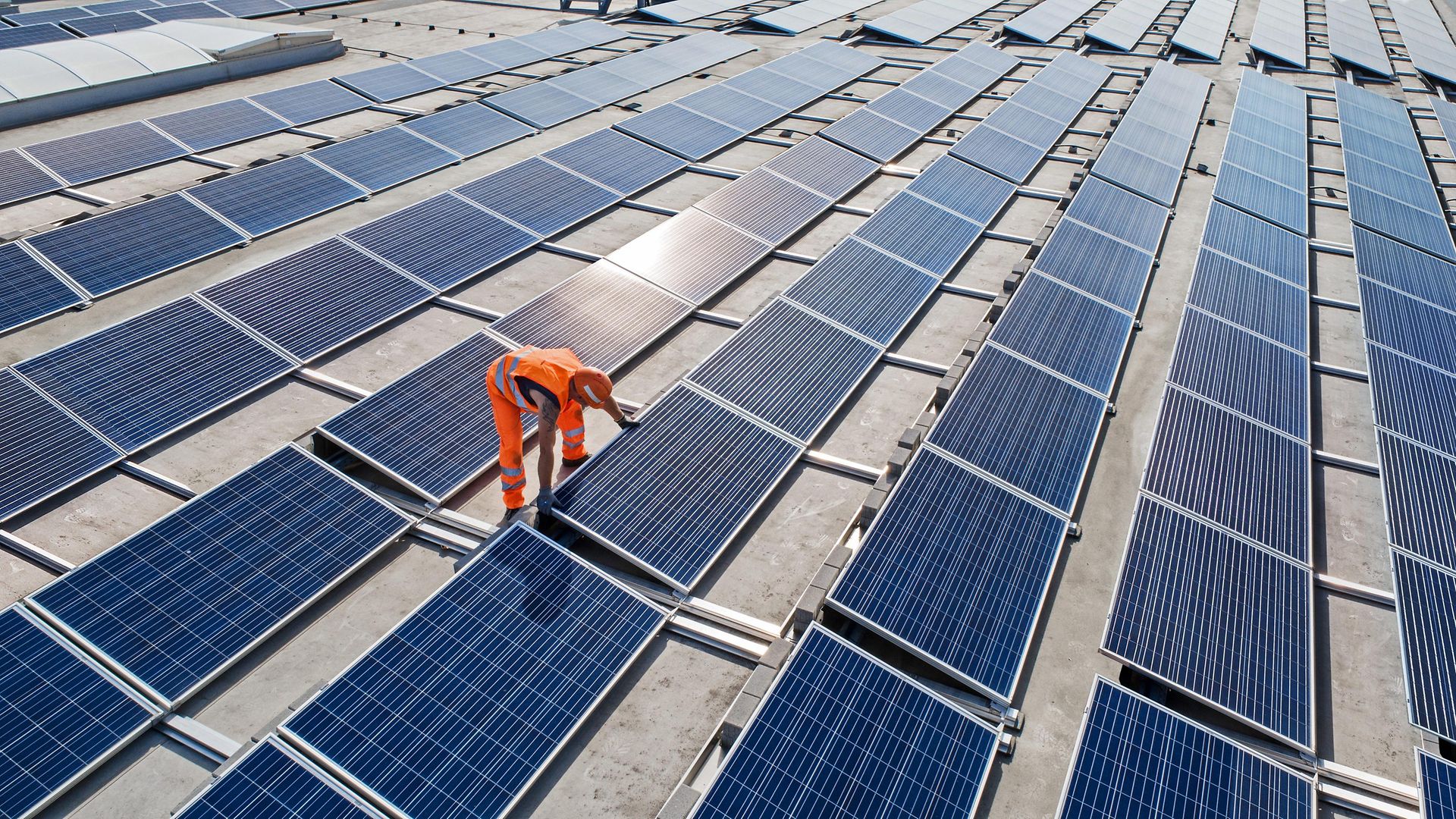 viele Photovoltaikplatten mit Mitarbeiter, der diese montiert