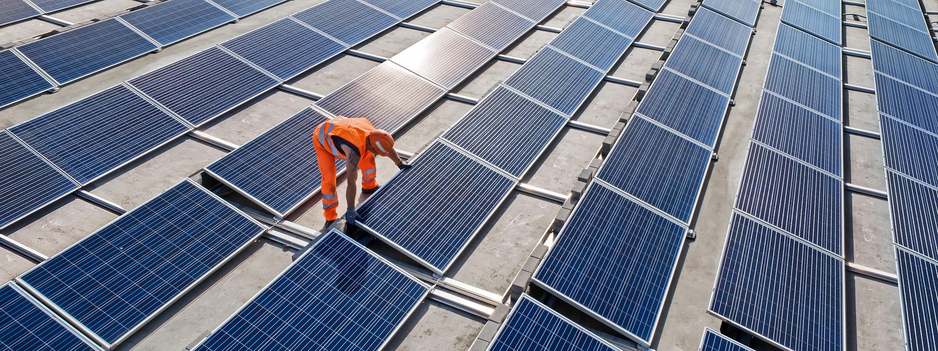 viele Photovoltaikplatten mit Mitarbeiter, der diese montiert