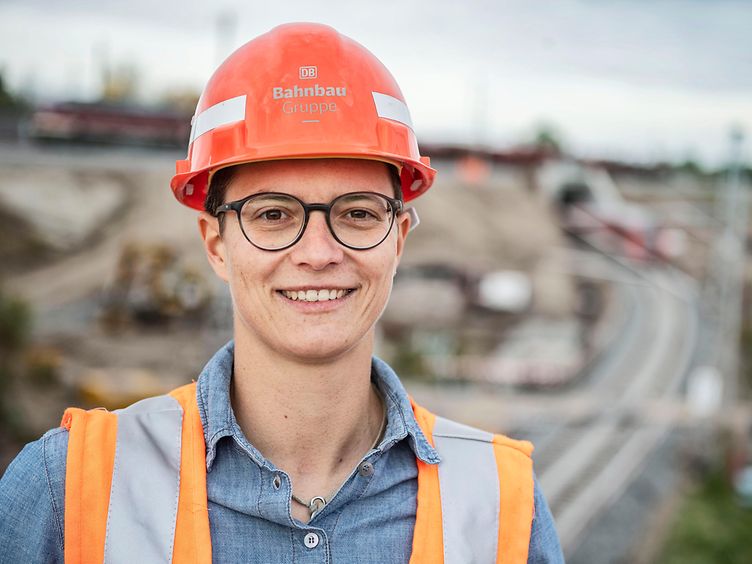Mitarbeiterin mit Helm Großbaustelle im Hintergrund