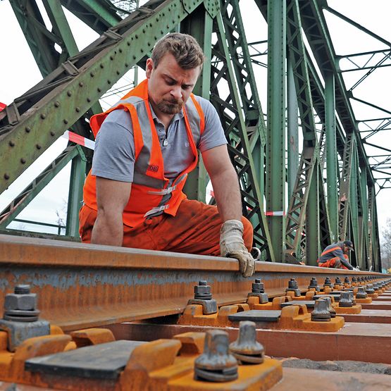 Mitarbeiter arbeitet am Gleis auf einer Bahnbrücke