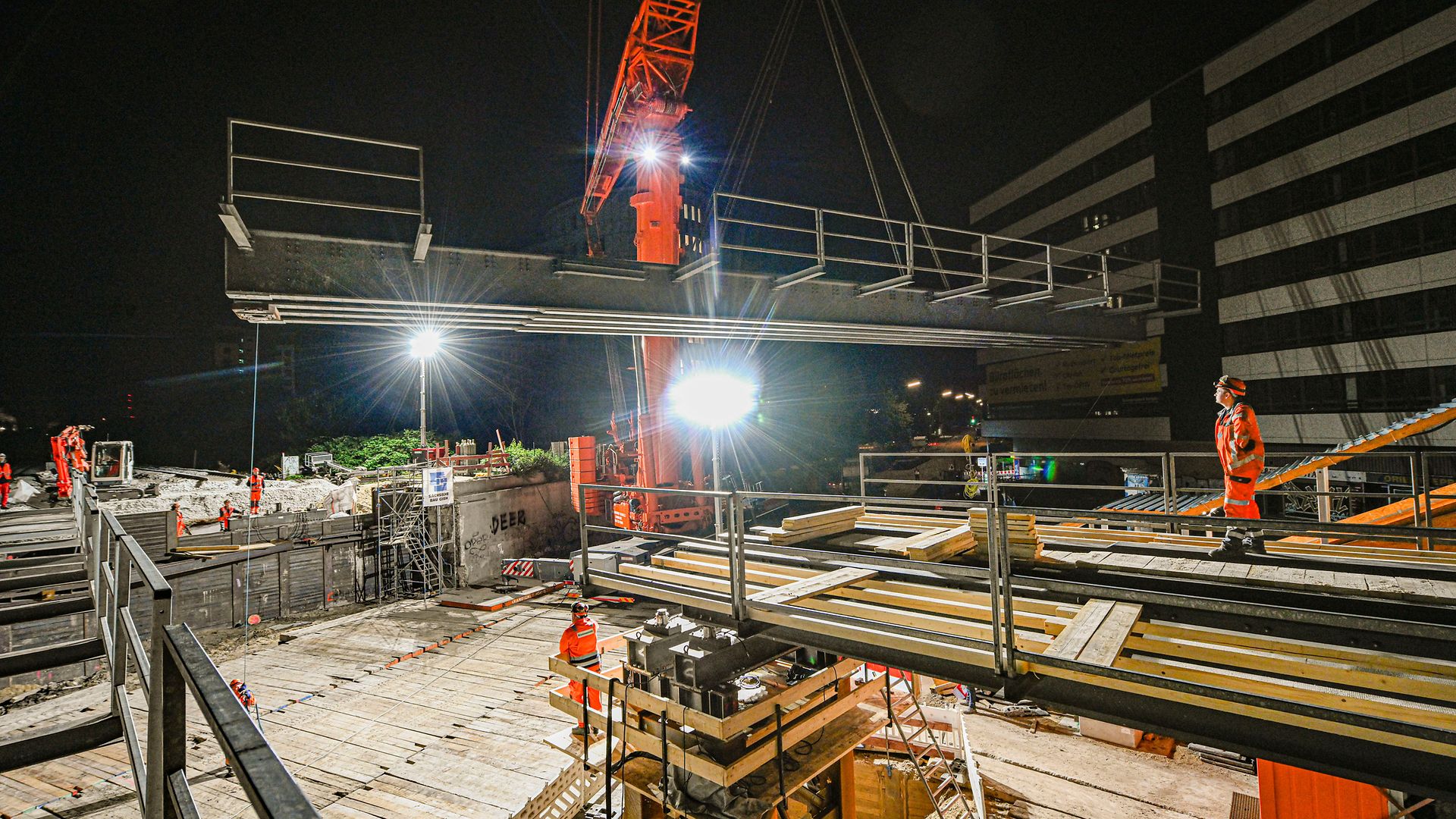 Einheben einer Zwillingsträgerhilfsbrücke mit einem Kran bei Nacht.