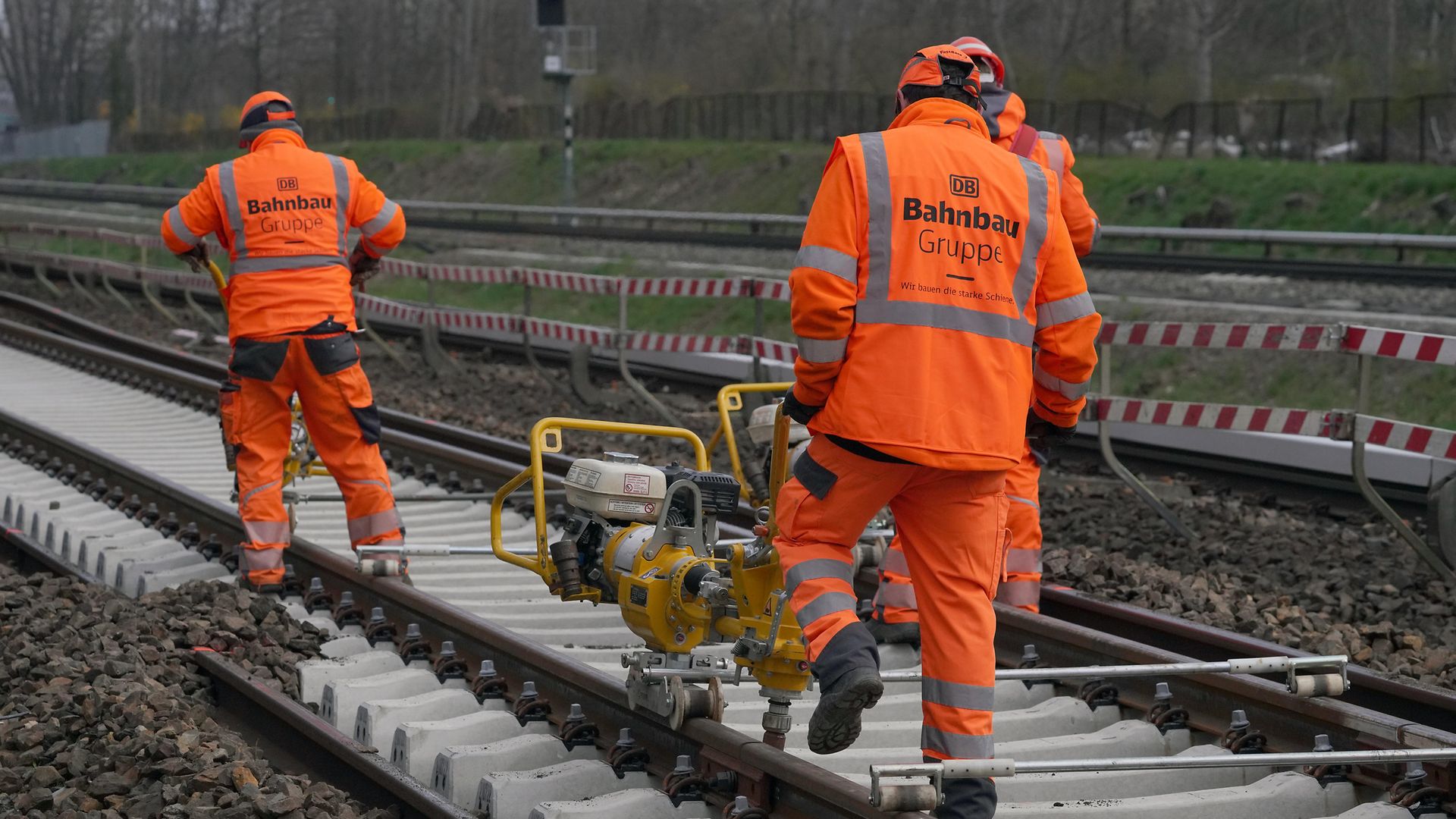 Zwei Gleisbauer auf der Schiene mit orangefarbener Schutzkleidung