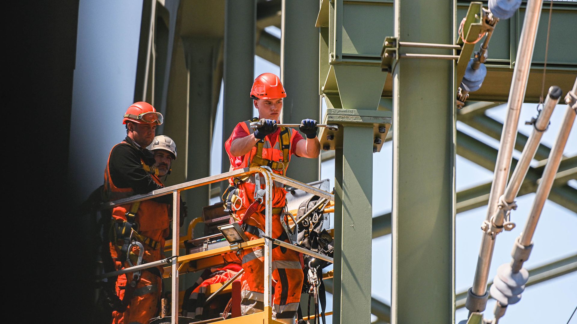 Metallbauer auf einer Hebebühne arbeiten an einer Brücke