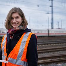 Lächelnde Frau mit Schutzweste an Gleisen