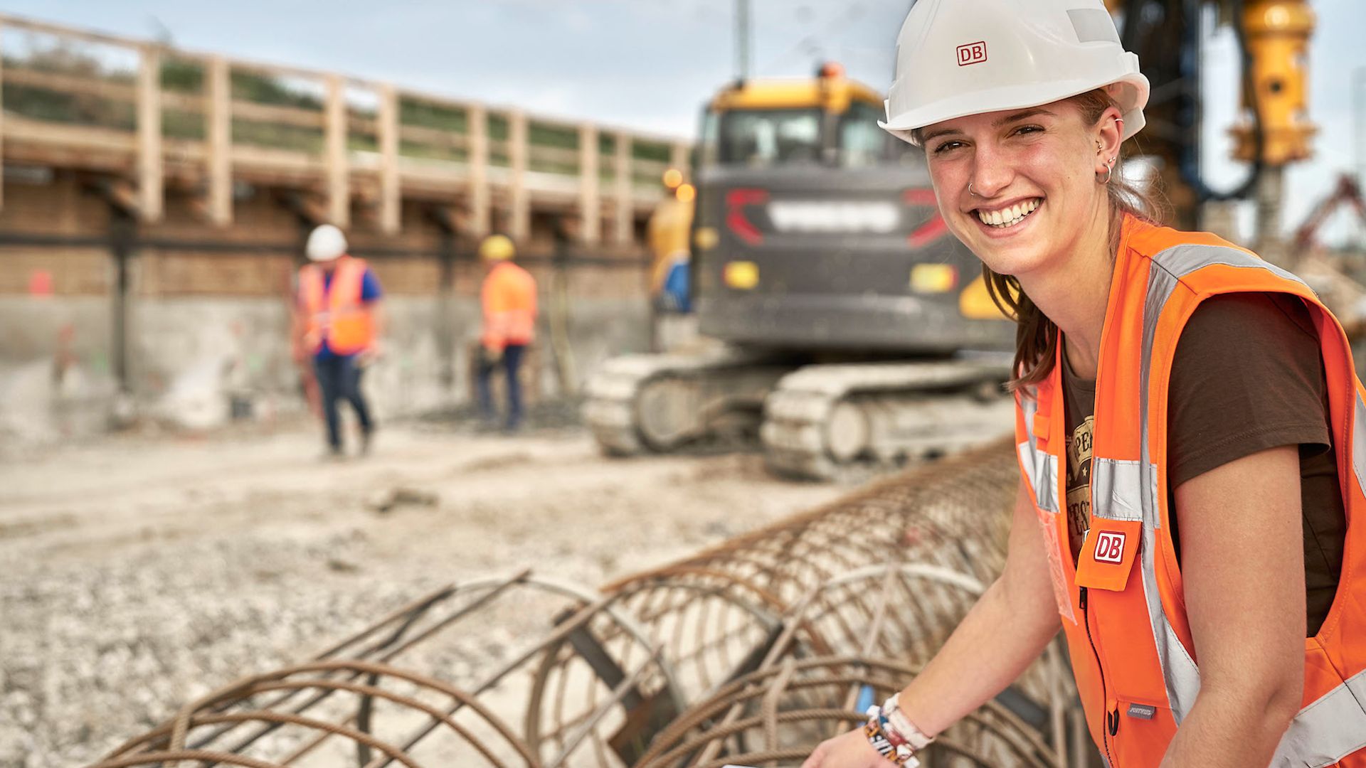Lächelnde Frau auf der Baustelle mit Bagger im Hintergrund