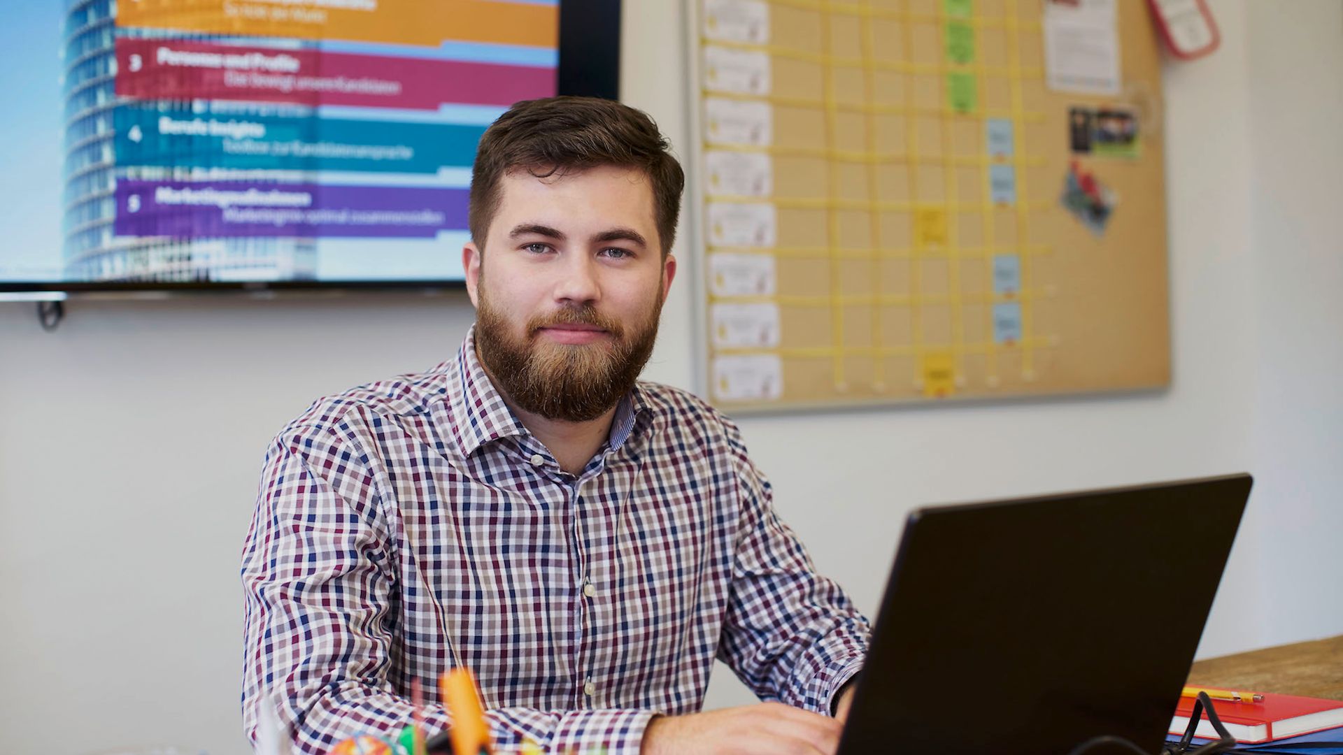 Mann sitzt im Büro vor dem Laptop